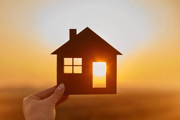 Woman hand holds wooden house against the sun. Solar energy. Children dreams. International day of families. Home protection insurance concept. Planning to buy property. A symbol for ecology. "nAffordable housing. Real estate agent offer house. Choose what's the best.